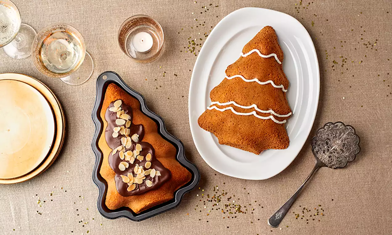 Bizcochos en forma de árbol navideño dorados y esponjosos, uno con glaseado de chocolate y almendras, otro decorado con líneas de azúcar