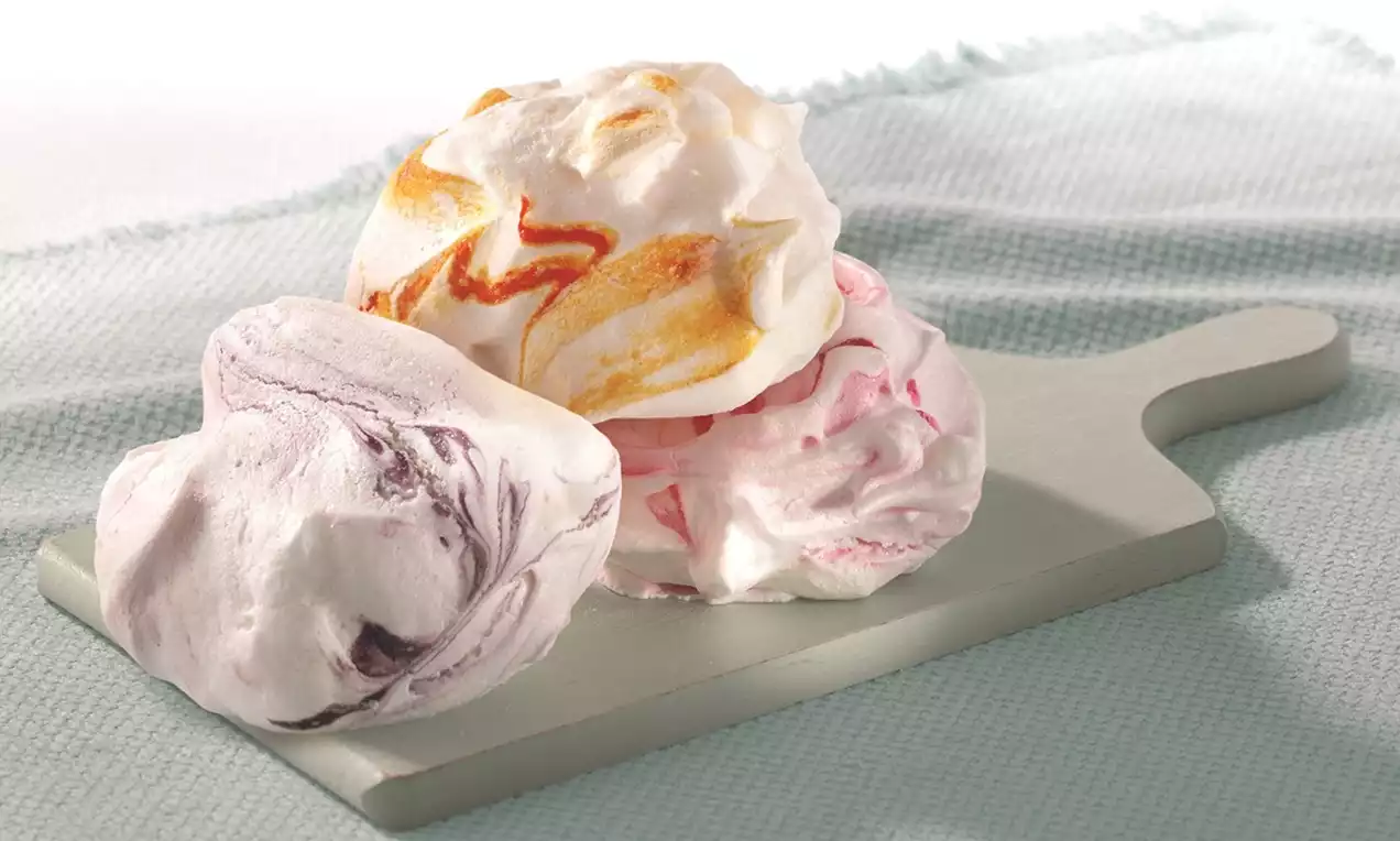 Marbled meringues with swirls of orange, purple, and pink, airy and irregularly shaped, arranged on a pale rectangular serving board