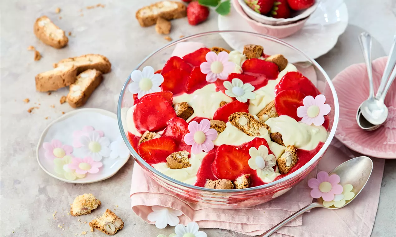 Ein geschichtetes Dessert im Glas mit frischen Erdbeeren, knusprigen Cantuccini-Stücken, cremigem Pudding und Mascarpone – dekorativ angerichtet als fruchtiger, sommerlicher Nachtisch