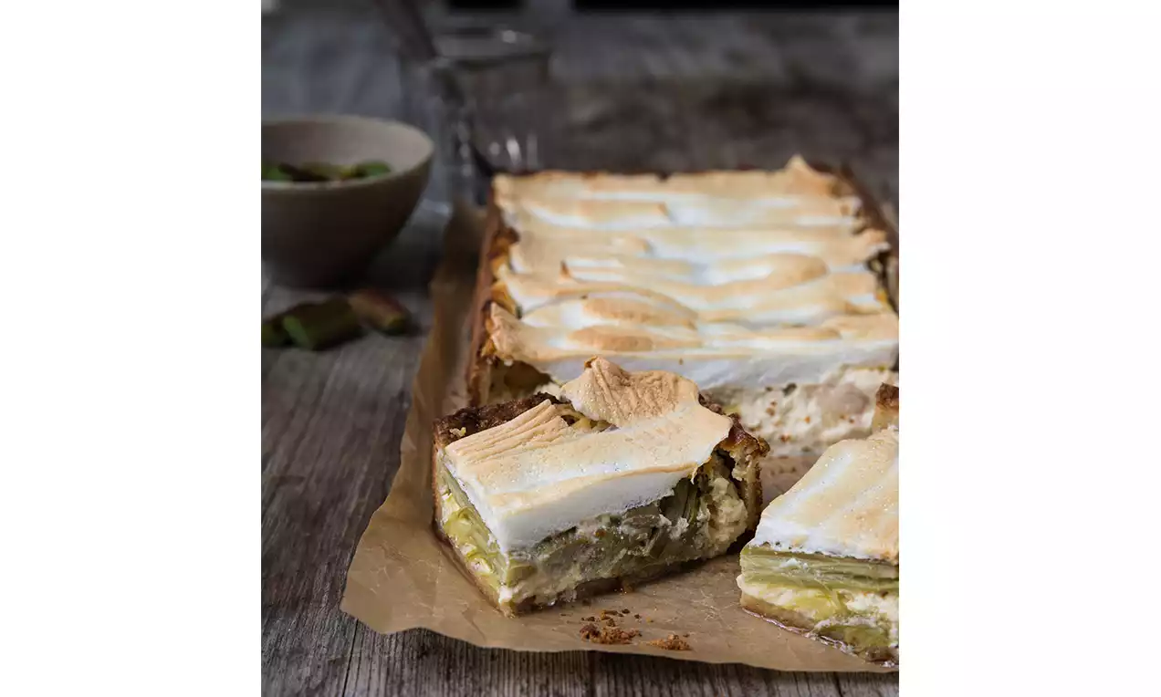 Crostata rettangolare con base dorata, ripieno verde di rabarbaro e soffice meringa bianca lievemente dorata disposta a onde