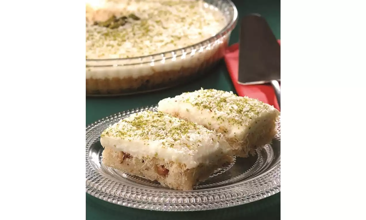 Kare dilimlenmiş, üstü ince Antep fıstığı serpilmiş, altı hafif kıtır kadayıflı, üstü yumuşak sütlü tavukgöğsü katmanlı tatlı