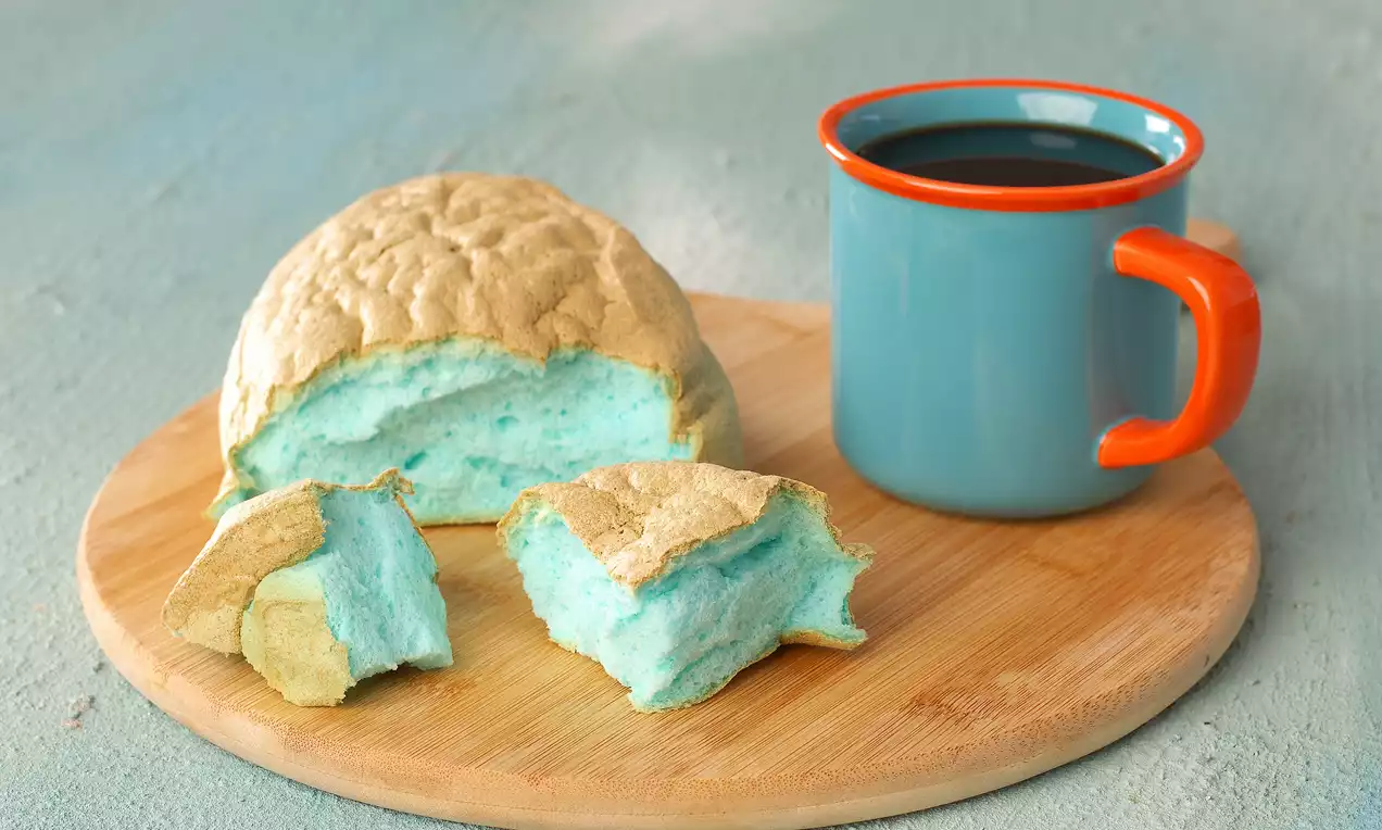 Altın rengi kabuklu, iç dokusu pamuk gibi yumuşak mavi bulut ekmek, ahşap tabakta turkuaz fincanda kahve eşliğinde