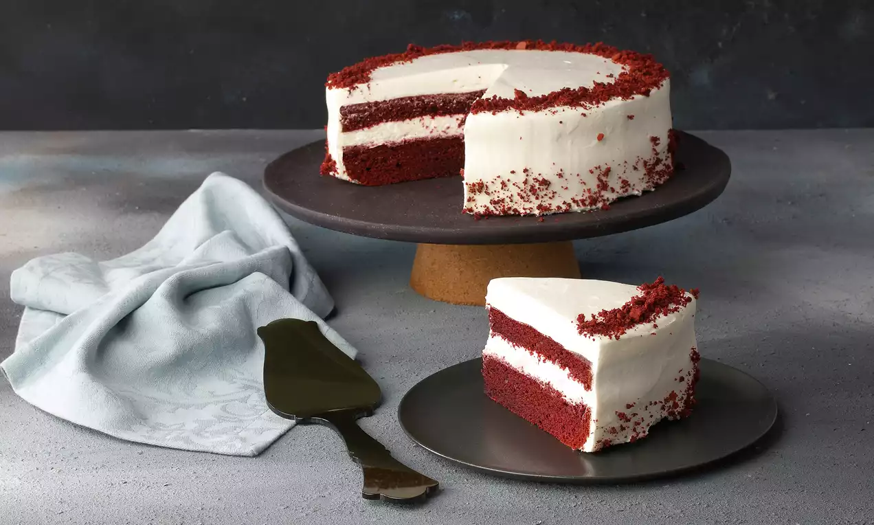 Kırmızı kadife katmanlar ve yoğun beyaz krema ile süslenmiş pasta, bir dilimi siyah tabakta sunulmuş şekilde işlenmiş sade görüntü