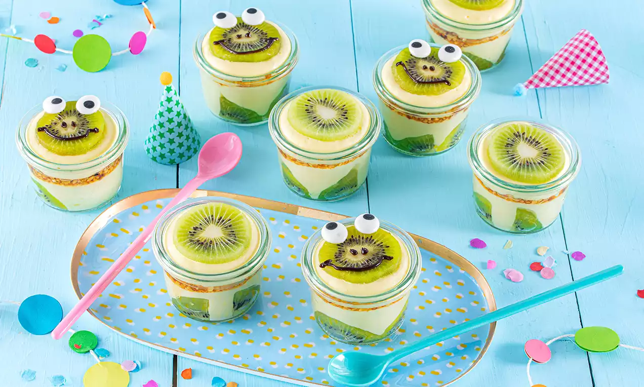 Cam bardaklarda kat kat dizilmiş, renkli soslarla bezenmiş kivi dilimleri ve sevimli göz süslemeleriyle sunulan ferah tatlılar