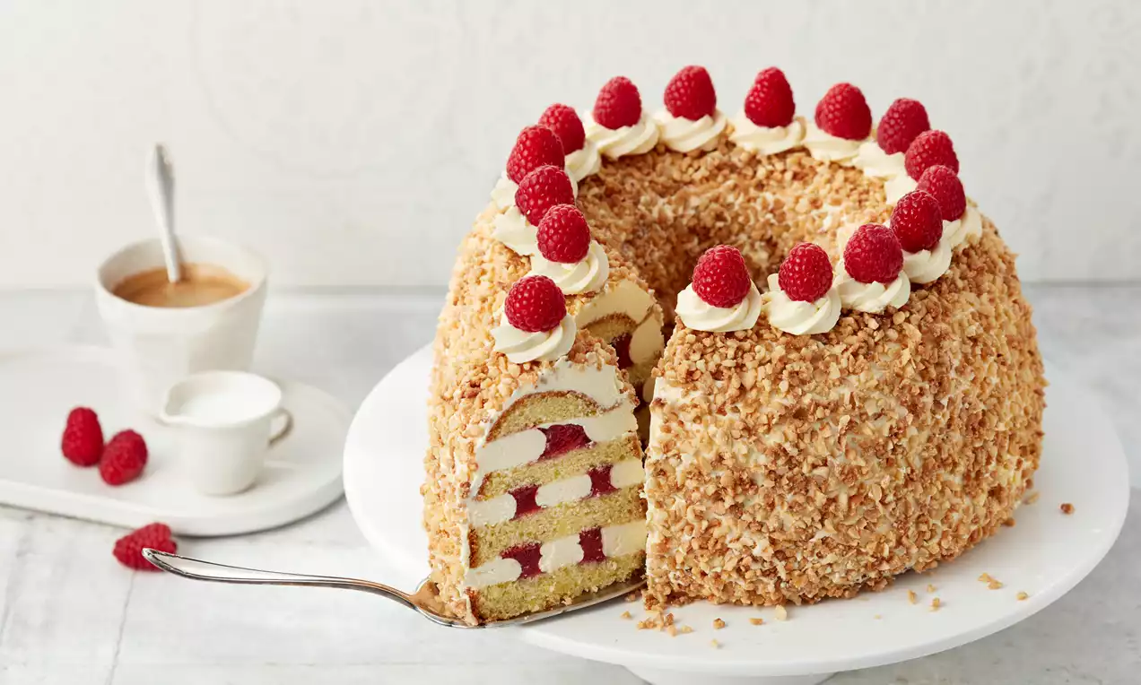 Frankfurter Kranz mit goldbraunem Rührteig, hellgelber Vanille-Buttercreme, roten Konfiturestreifen und knusprigem Mandelkrokant