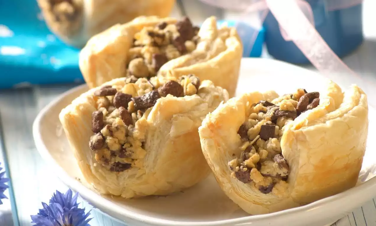 Čokoladni paketići od zlatno-smeđeg lisnatog tijesta, punjeni hrskavom mješavinom müslija i čokoladnih komadića, posluženi na bijelom tanjuru