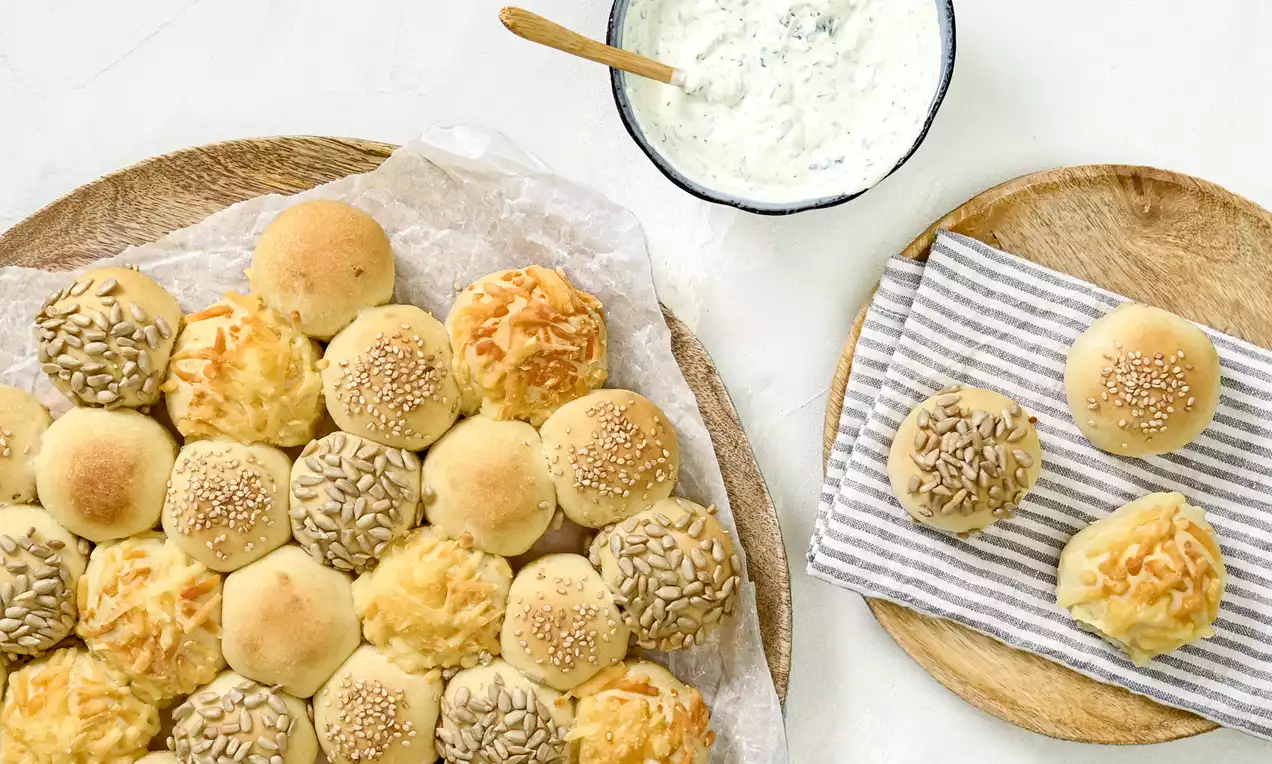 Partysonne aus goldbraunen Dinkelbrötchen, mit Sesam und Körnern bestreut, in Sonnenform auf einem Backblech angerichtet