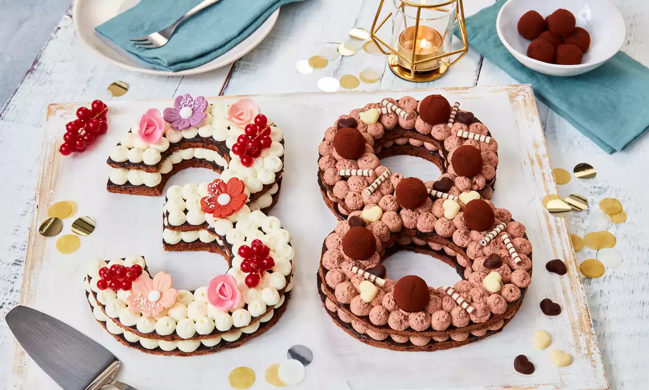 Zahlentorte in Form einer 38 mit abwechselnden Schokoladen- und Vanille-Creme-Schichten, dekoriert mit Früchten, Pralinen und Zuckerperlen