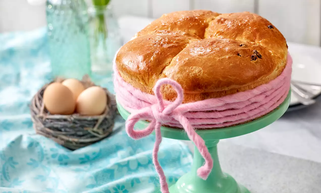 Zlatnosmeđa pinca s glatkom sjajnom površinom, ovalnog oblika, na svijetlozelenom stalku ukrašena ružičastom vunenom trakom