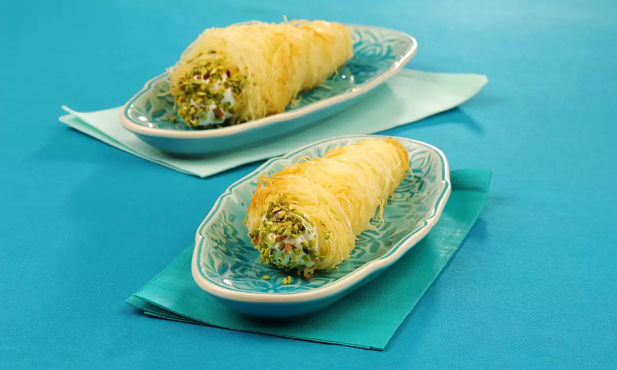 Altın rengi çıtır kadayıfla sarılmış, kıvamlı kaymak dolgusuyla uç kısımları ince çekilmiş Antep fıstığıyla süslenmiş torpil tatlısı