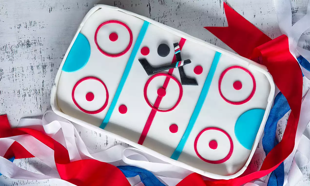 Dort v tvare hokejového klziska s bielym povrchom, červenými a modrými čiarami a kruhmi, dekorovaný farebnými stuhami na podklade