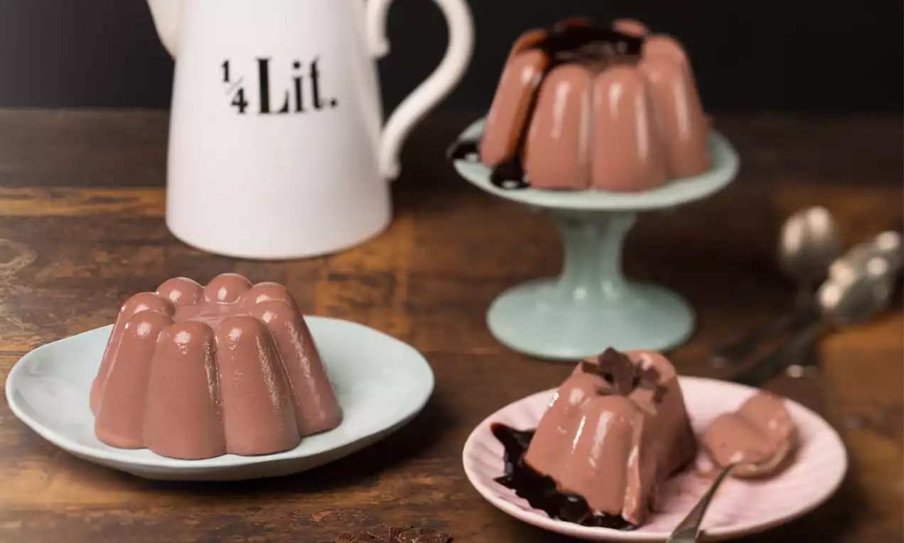 Schokopudding in zart schokoladenbrauner Farbe mit glänzender Oberfläche, arrangiert auf Tellern mit Schokoladensauce und vintage Dekoration