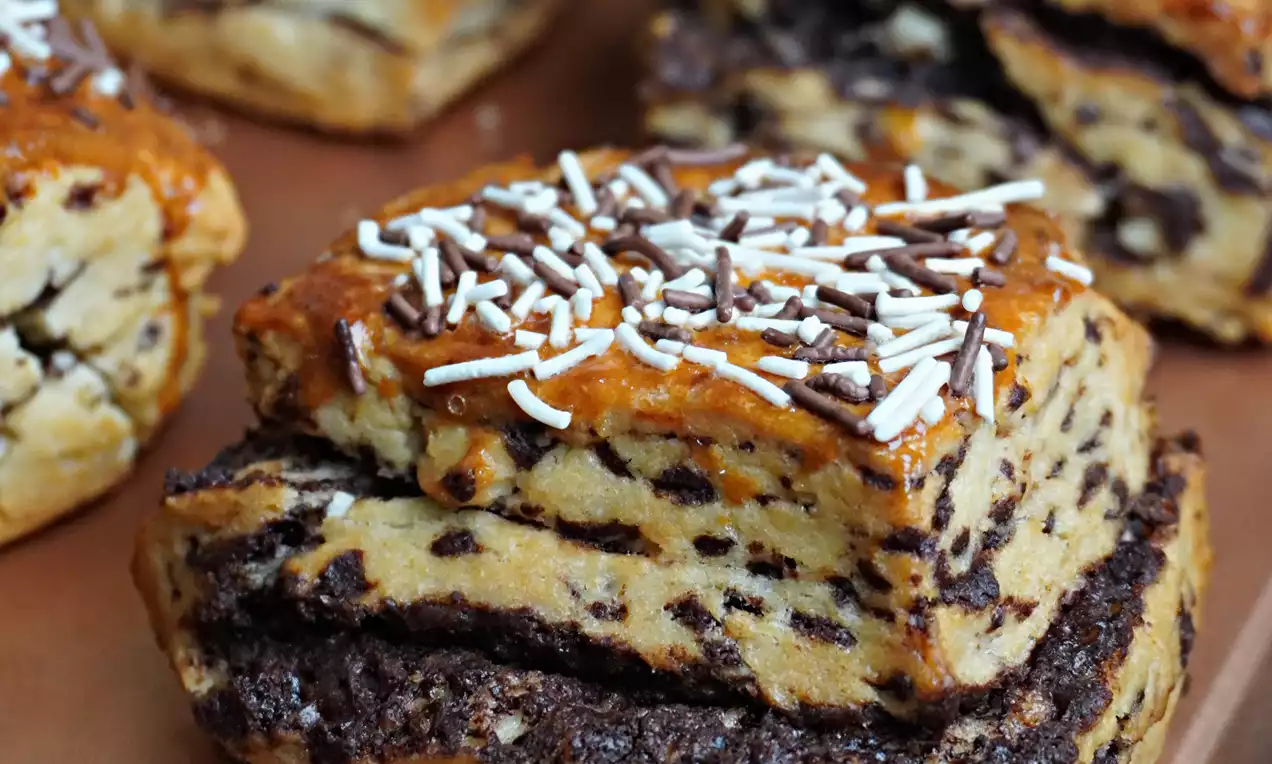 Golden brown layered chocolate buttermilk scones topped with white sprinkles on a copper tray with a rich speckled texture