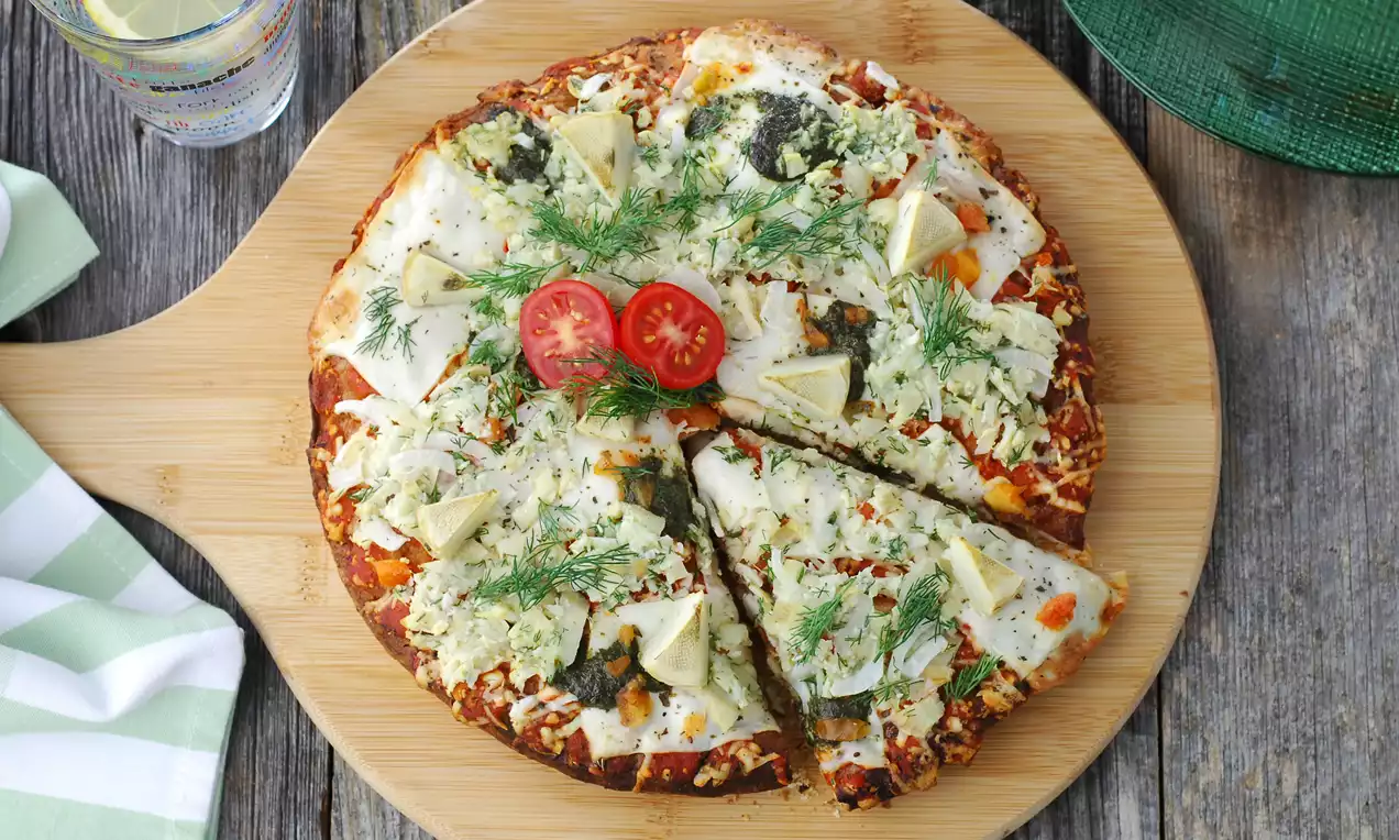 Ronde houtovenpizza met een dunne korst, gesmolten mozzarella, artisjokharten, verse dille, citroenpartjes en cherrytomaat op een houten plank