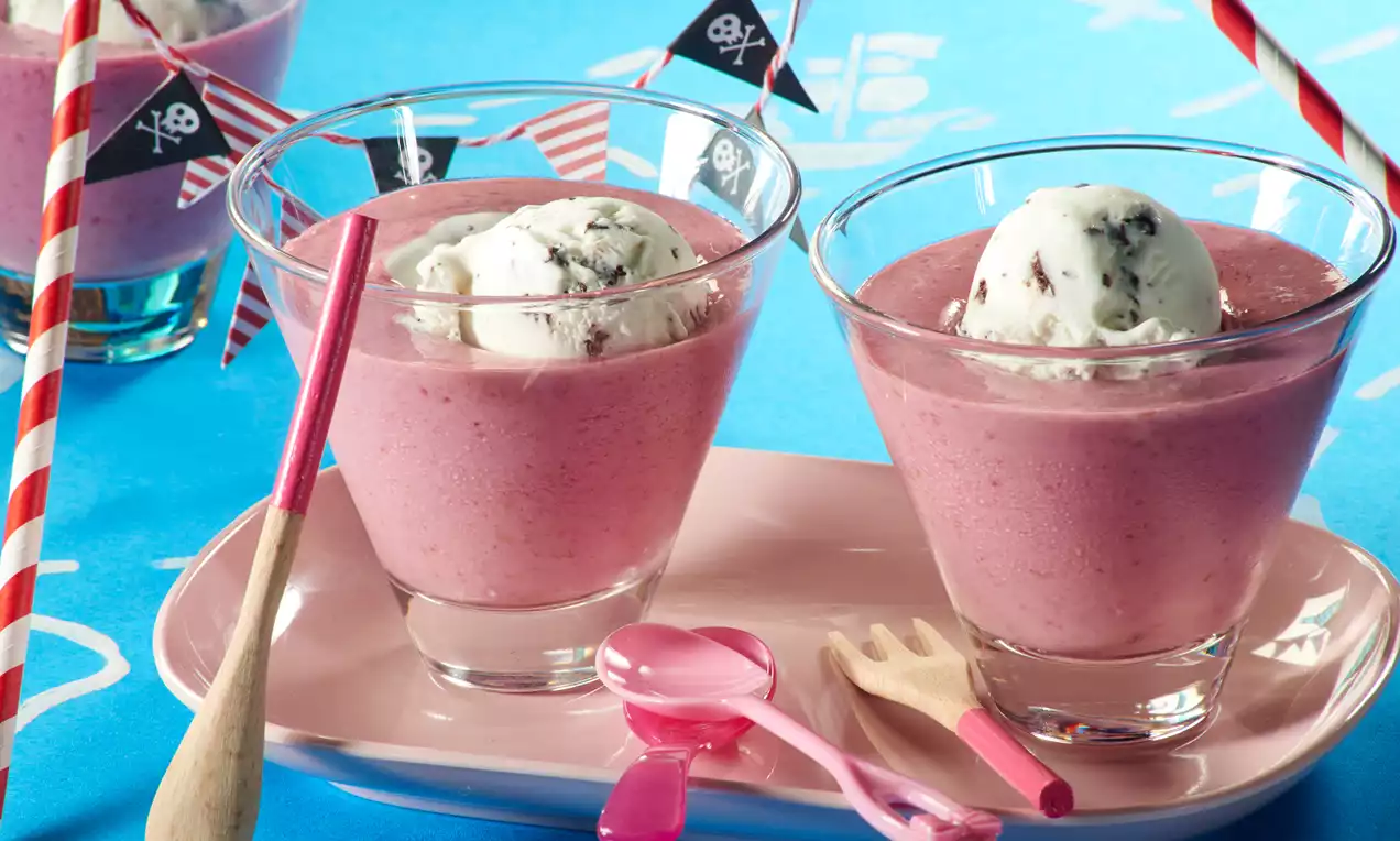 Pembe çilekli içecekler cam bardaklarda, dondurma topları, korsan bayrakları, renkli kaşıklar ve pembe porselen tabakla sunulmuş