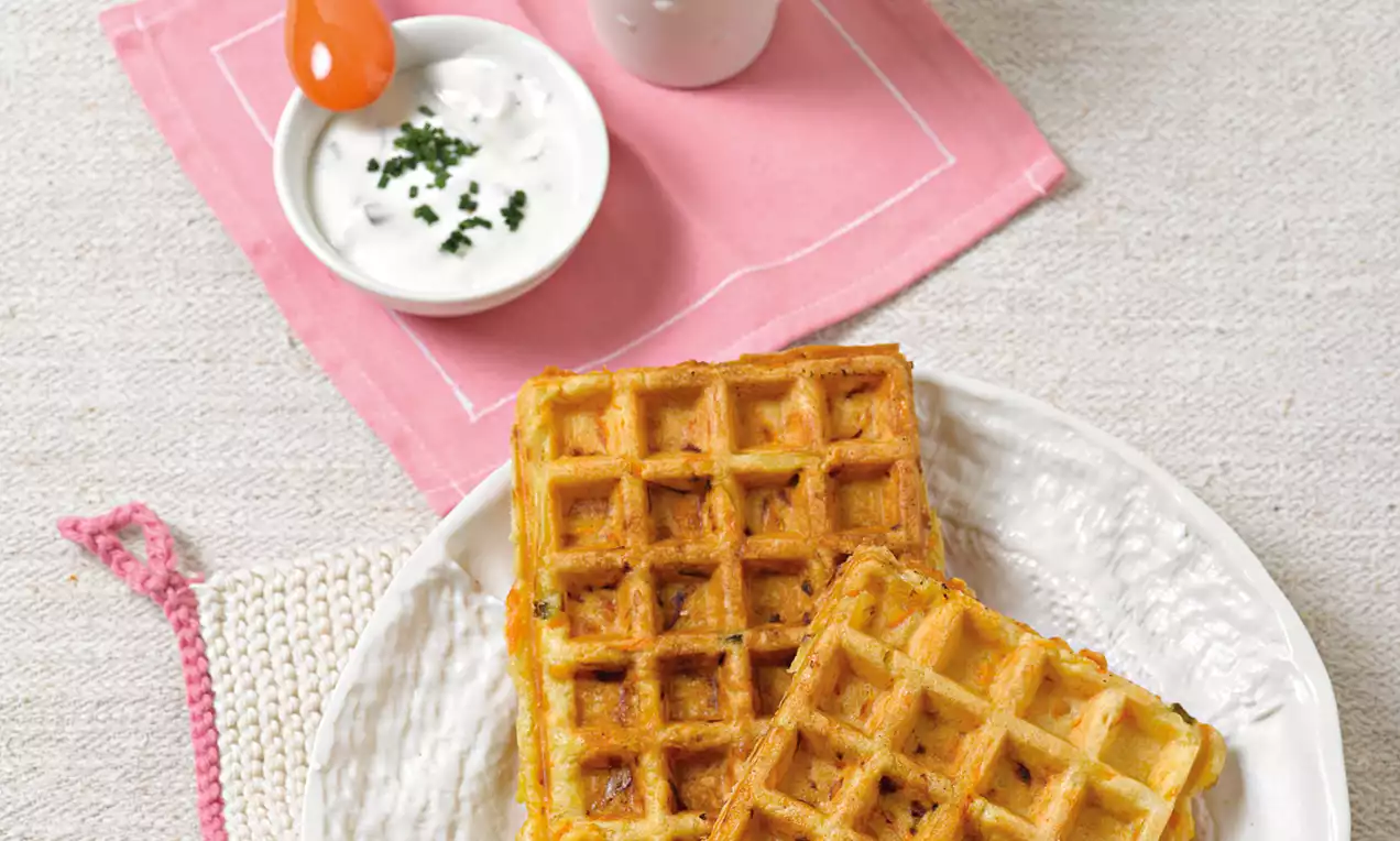 Goldbraune, rechteckige Waffeln mit lockerer Textur auf einem weißen Teller, serviert mit cremigem Dip in einer kleinen Schale