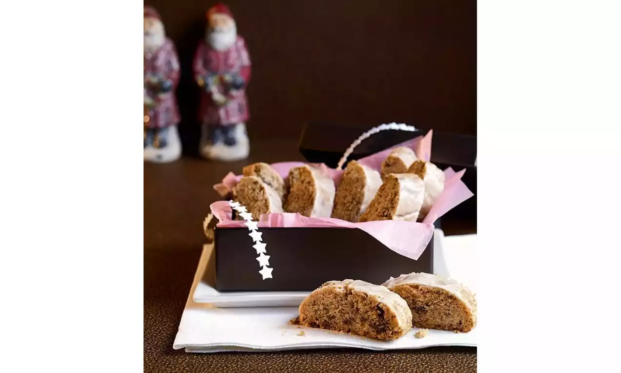 Koyu renk bir kutuda pembe kâğıtlarla sunulan beyaz kaplamalı dilimler, ön planda kahverengi zemin üzerinde servis edilmiş