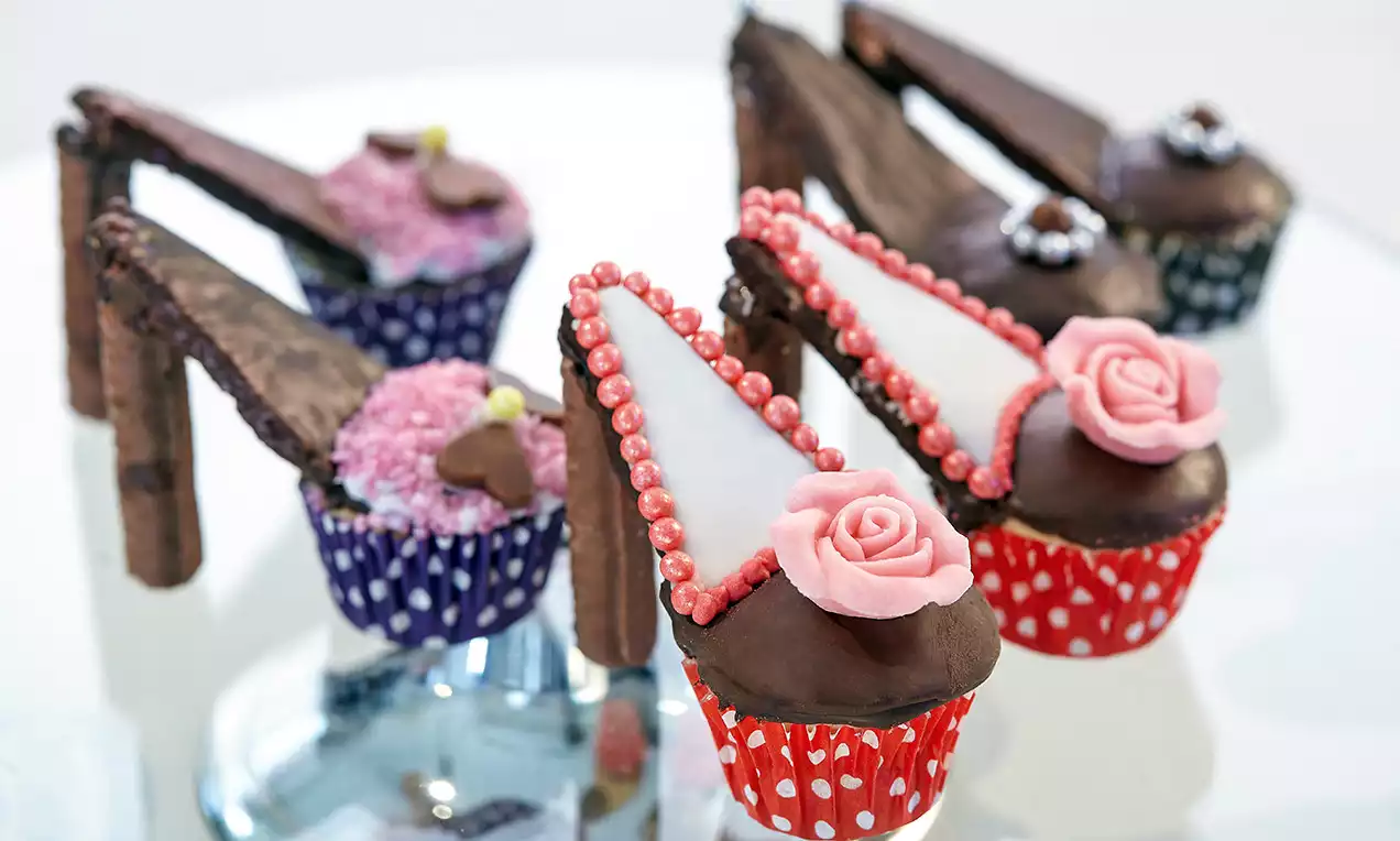 Cupcake a forma di scarpetta con base colorata a pois, tacco di biscotto al cioccolato e decorazioni floreali di pasta di zucchero rosa