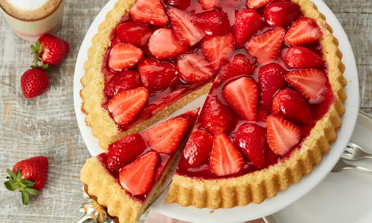 Obstboden mit saftigem goldbraunem Rührteig, dicht belegt mit glänzenden roten Erdbeeren, blauen Heidelbeeren und Aprikosen