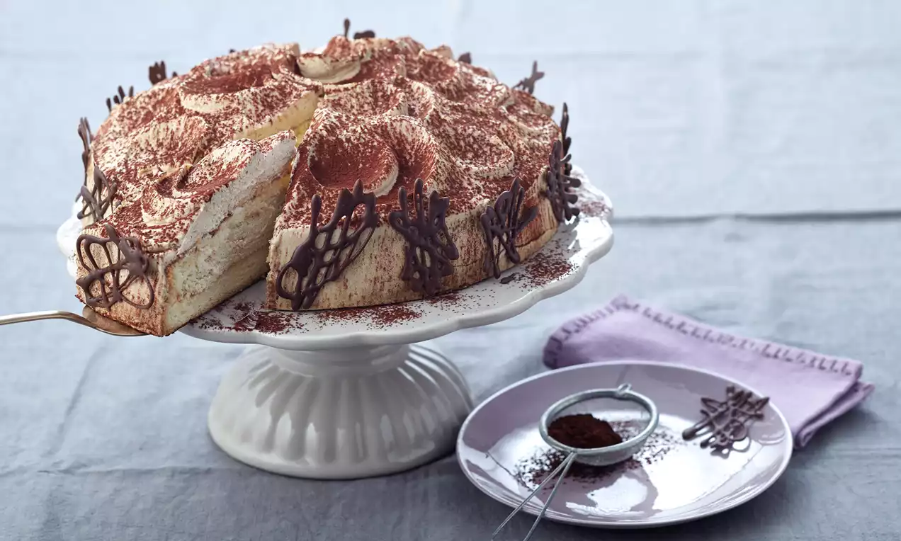 Cappuccino-Sahne-Torte mit kuppelförmiger Sahnecreme, hellbraunem Biskuitboden, Kakaostaub und Schokoladenraspeln