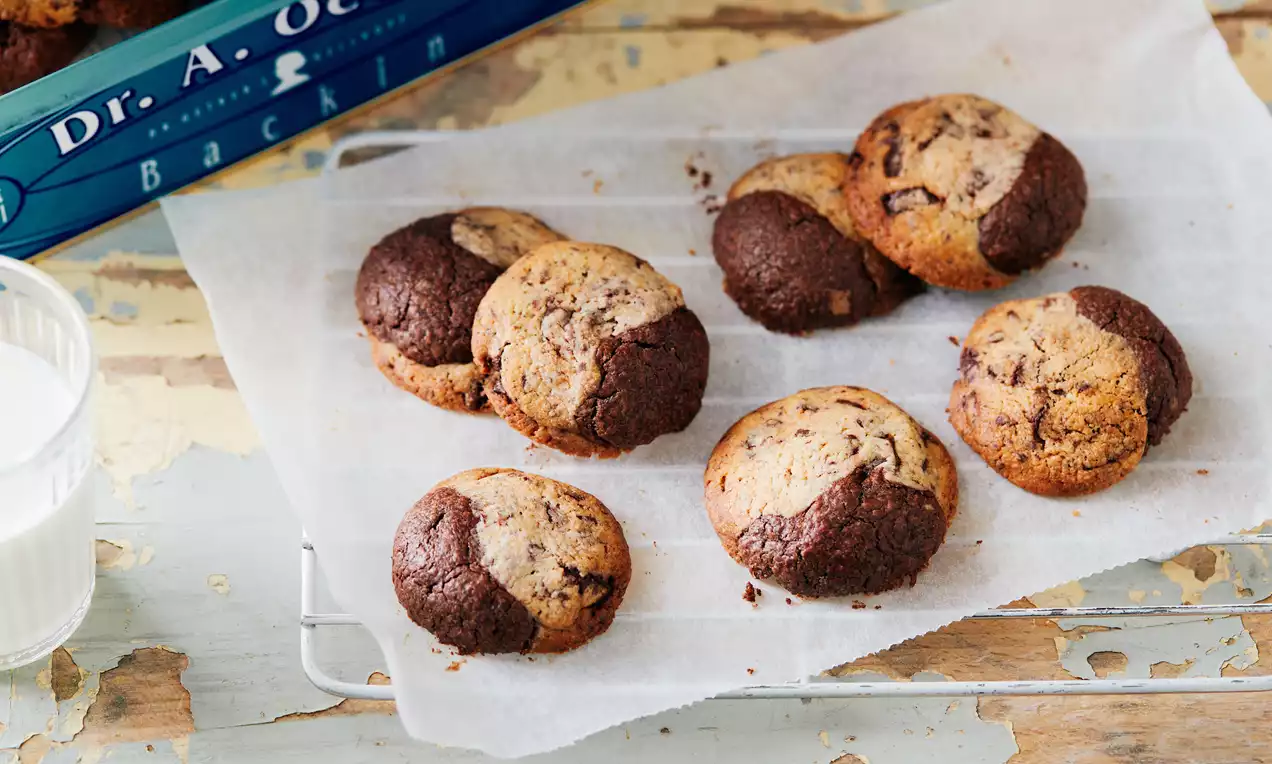 Ronde brookies met een gemarmerde mix van bruine chocolade- en goudbruine koek tekstuur, liggend op wit bakpapier op een rooster