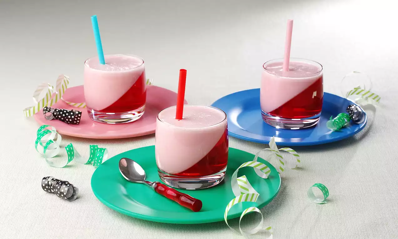 Şeffaf bardaklarda iki katmanlı pembe ve kırmızı milkshake, renkli pipetler ve tabaklarda metal kaşık ile süslü çağdaş sunum