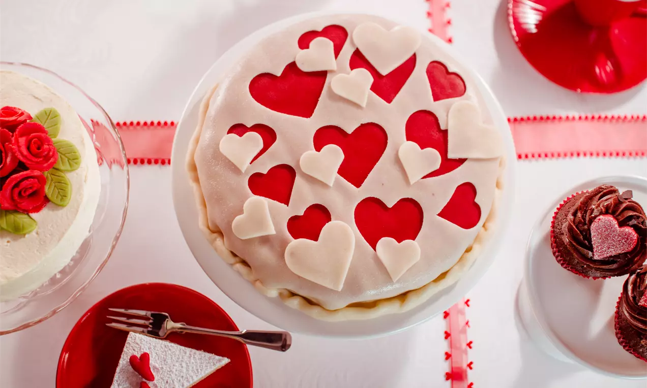 Torte mit hellem Marzipan eingedeckt, lässt rote Herzen durchscheinen