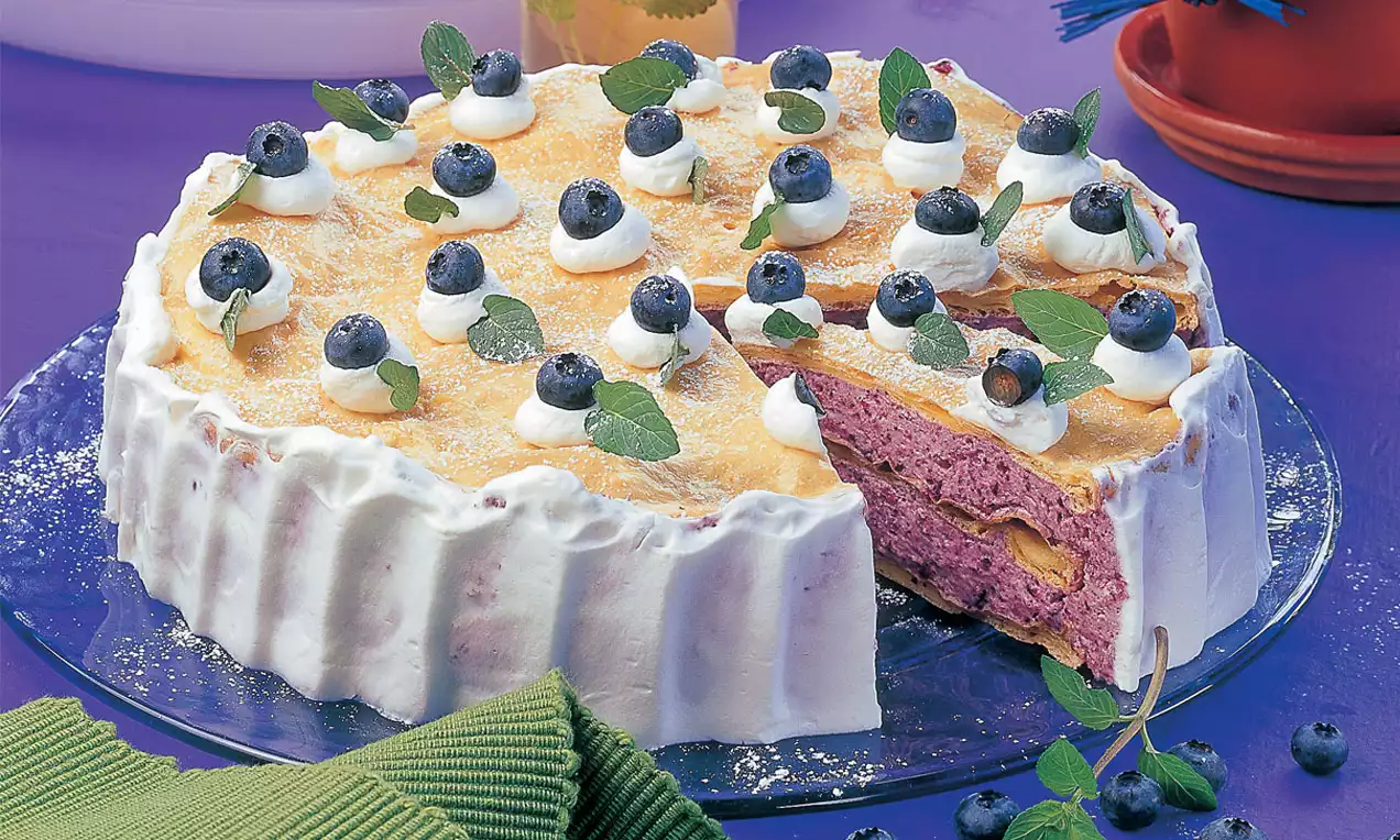 Heidelbeer-Torte mit lilafarbenem Heidelbeercreme-Boden, schneeweißer Sahneverkleidung, goldener Oberfläche und frischen Heidelbeeren