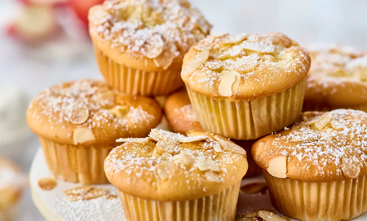 mehrere Apfel-Quark-Muffins gestapelt - Muffins mit saftigen Apfelstücken, Quark im Teig und gerösteten Mandeln obendrauf – einfaches Muffin-Rezept für Frühstück, Snack oder Kaffeepause.