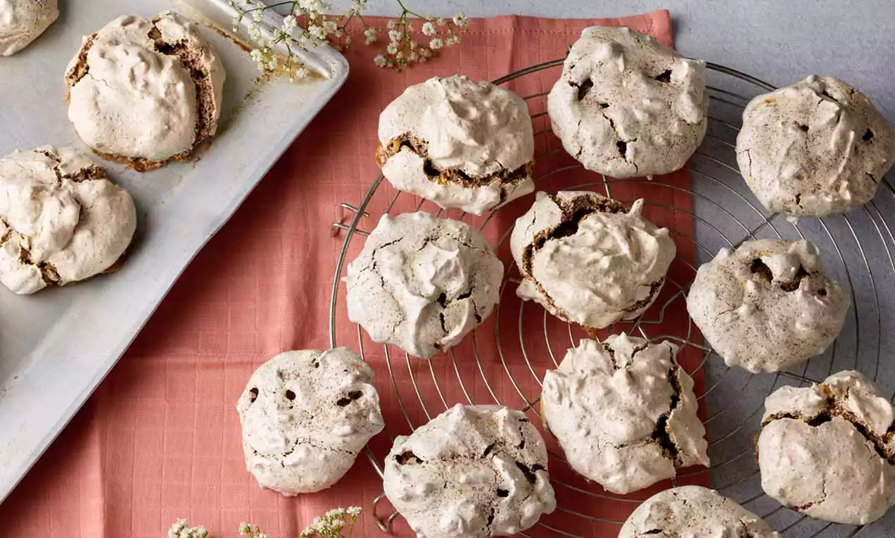 Helle, knusprige Wespennester mit rissiger Oberfläche und zarter Textur auf einem Kuchengitter und Blech, arrangiert auf rosa Stoff