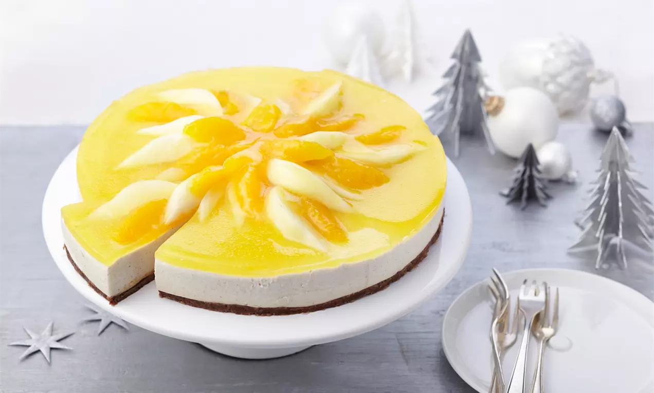 Adventstorte mit weißer Frischkäsefüllung auf braunem Boden, belegt mit gelber Geleecreme und Birnenstücken auf weißer Tortenplatte