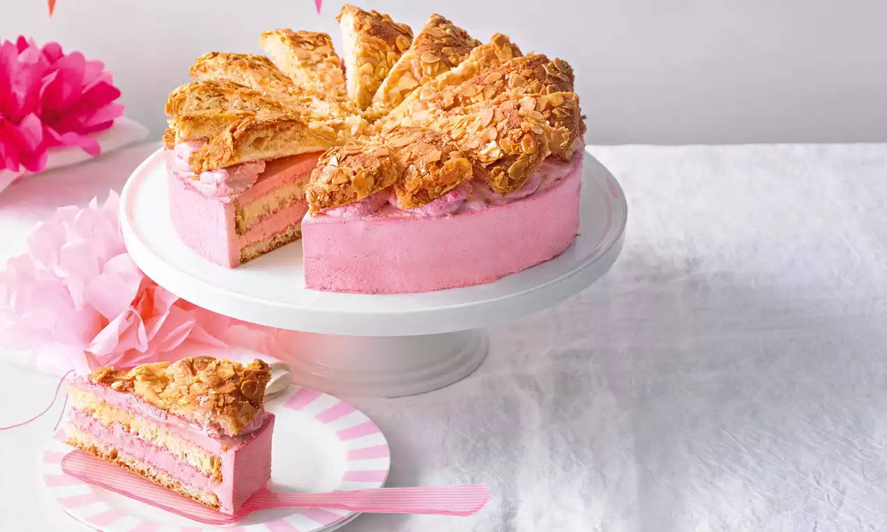 Pčelinji ubod s nježno ružičastom kremom, slojem biskvita i hrskavim zlatno smeđim bademovim koricama na bijelom stalku za tortu