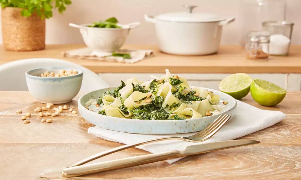 Nudeln mit Spinat, cremig vermengt mit leuchtend grünem Blattspinat, bestreut mit goldbraunen Pinienkernen und frisch gehobeltem Parmesan
