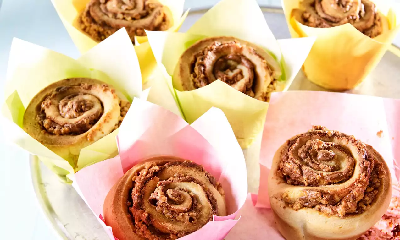 Karamelové šneky zlatohnedej farby, špirálovitého tvaru, s jemne chrumkavým povrchom, uložené v farebných papierových košíčkoch na tanieri