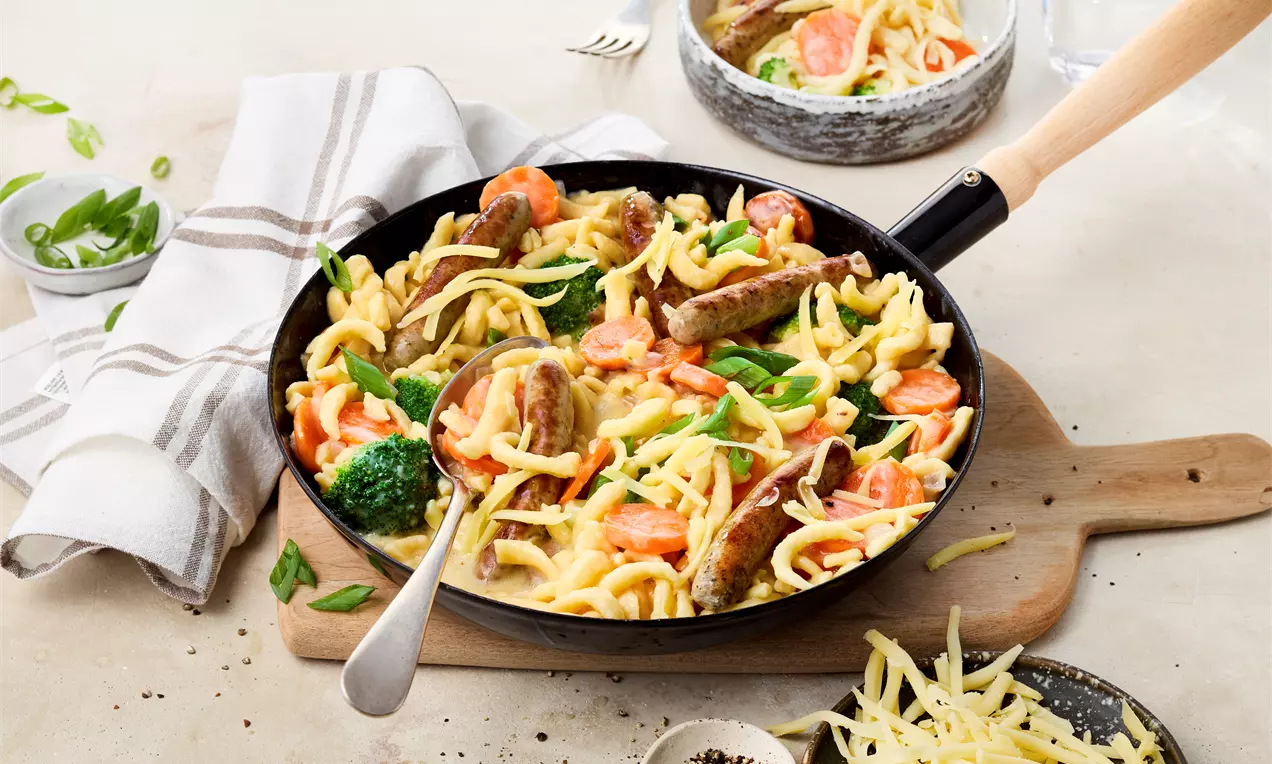 Bunte Spätzlepfanne mit cremiger Sauce, Brokkoli, Möhren, würzigen Würstchen und geschmolzenem Bergkäse – ein schnelles, herzhaftes Gericht voller Geschmack für die ganze Familie.
