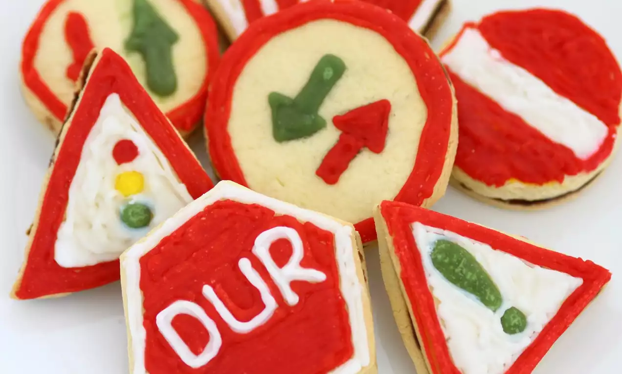 Trafik işaretlerine benzeyen kurabiyeler, kırmızı, yeşil ve beyaz renklerde şeker hamuru ile süslenerek detaylı şekilde dekore edilmiş