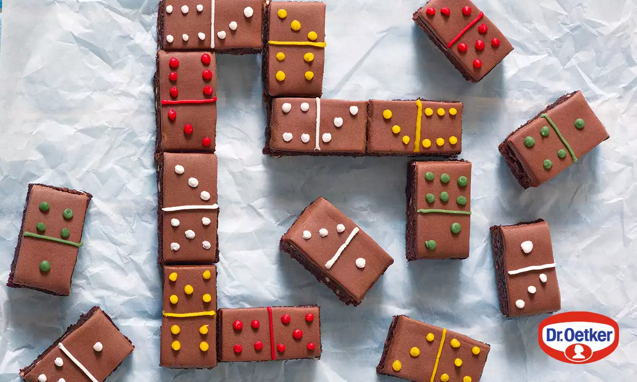 Čokoládové rezy obdĺžnikového tvaru, usporiadané ako domino, zdobené farebnými bodkami a čiarami na jemnom papieri