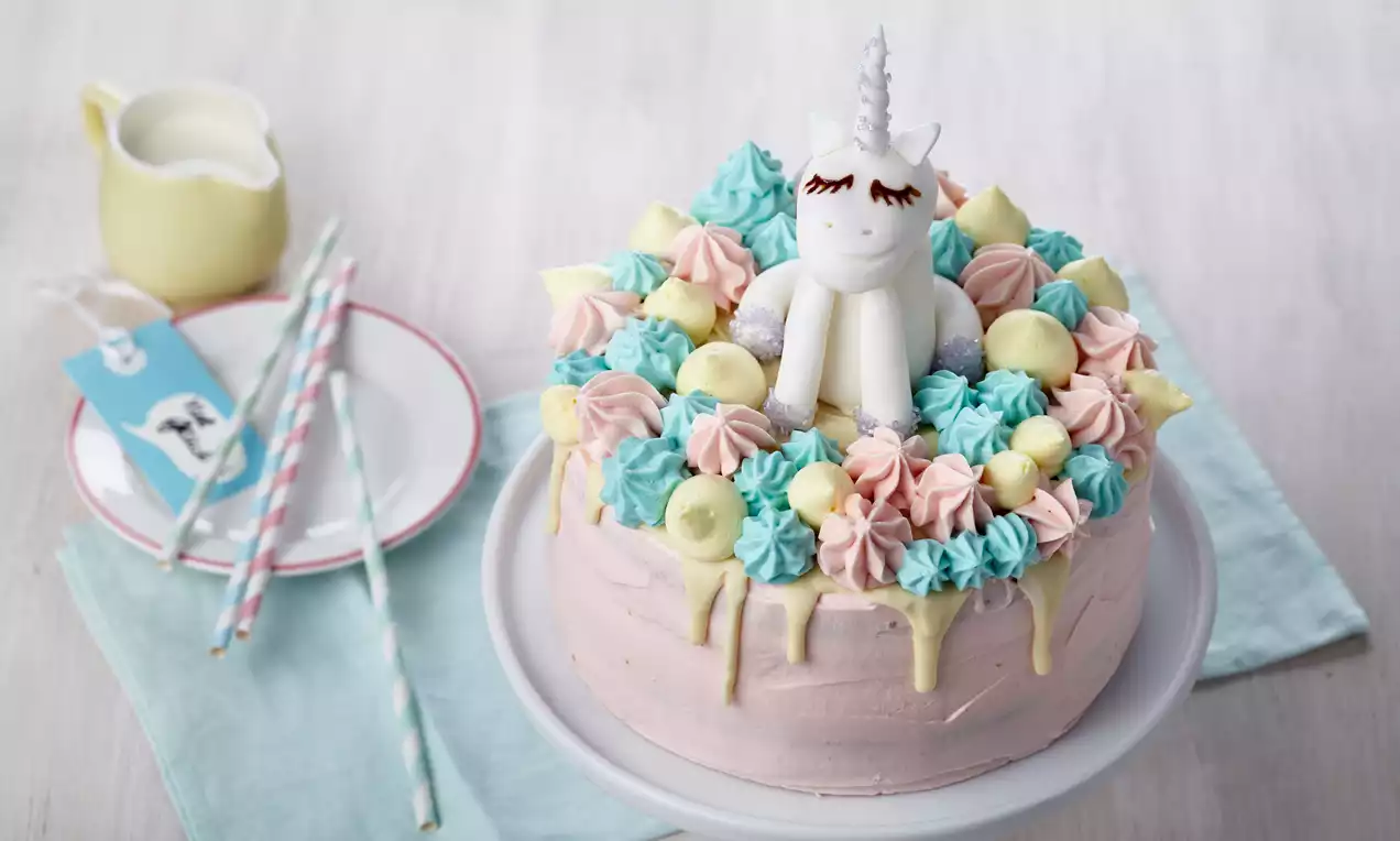 Regenbogen-Einhorntorte mit bunten Schichten, weißer Schokolade, pastellfarbener Buttercreme-Mähne, Zucker-Einhorn und goldener Hornspitze