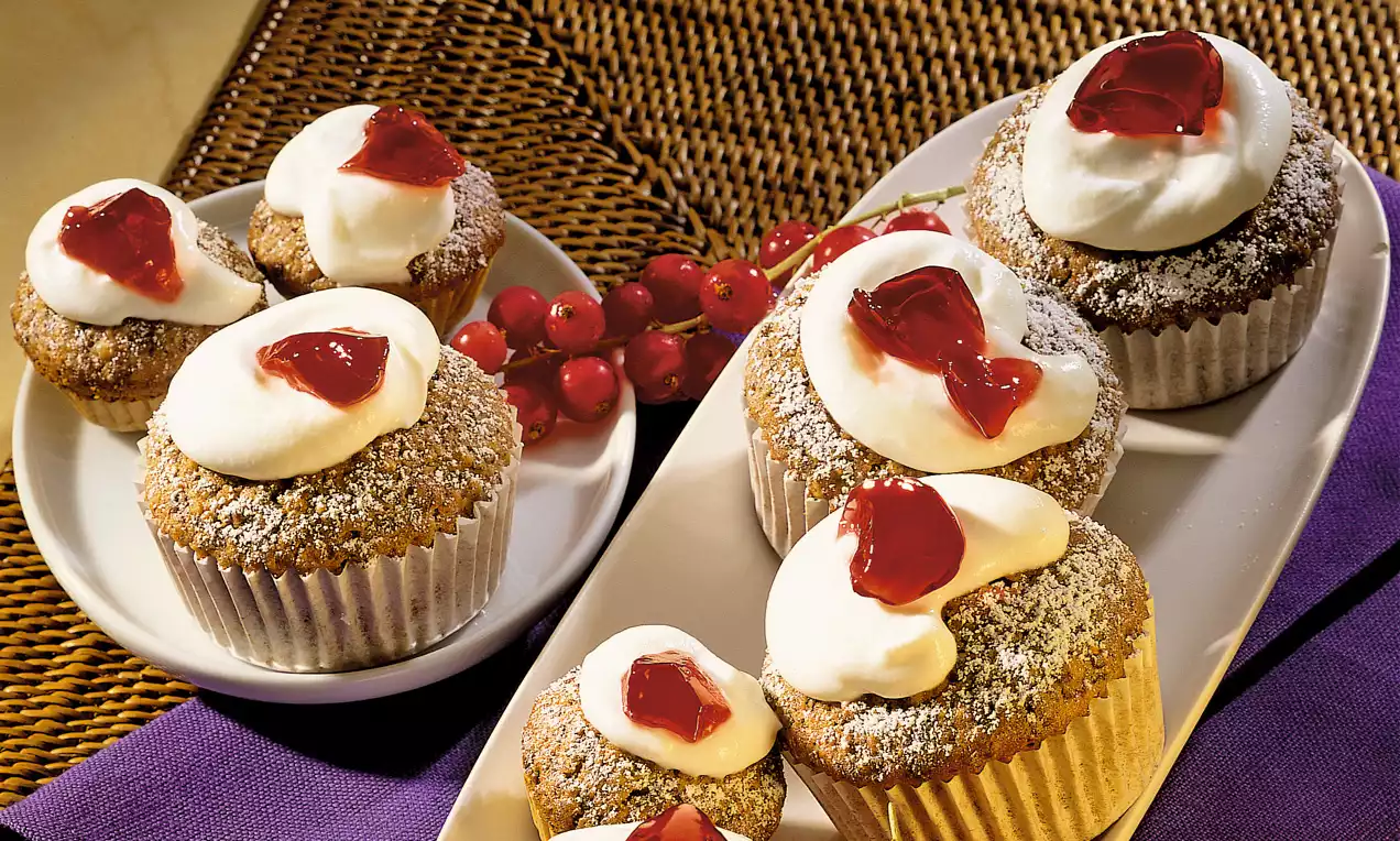 Tortini di pumpernickel scuri con dolce consistenza friabile, decorati con panna bianca soffice e salsa rossa su piatto bianco accanto a ribes