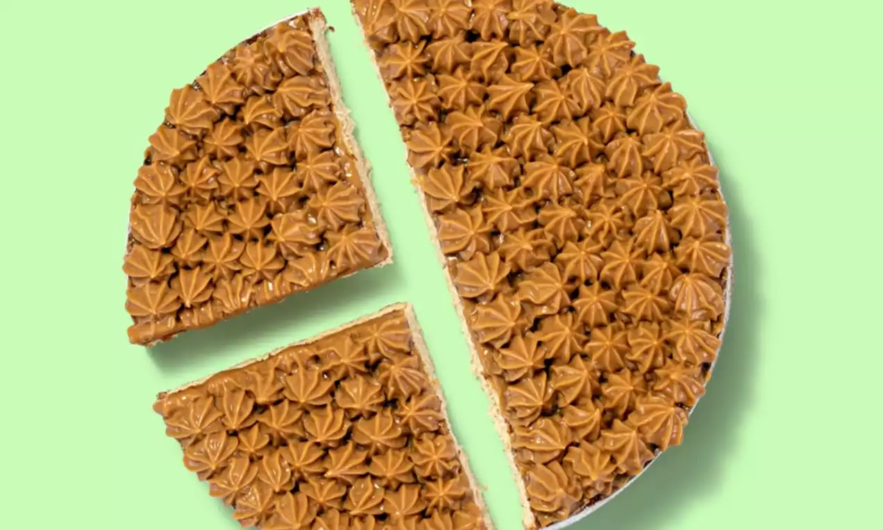 Bolo redondo coberto com rosetas de doce de leite cor caramelo, fatias cortadas mostrando camadas internas sobre fundo verde claro