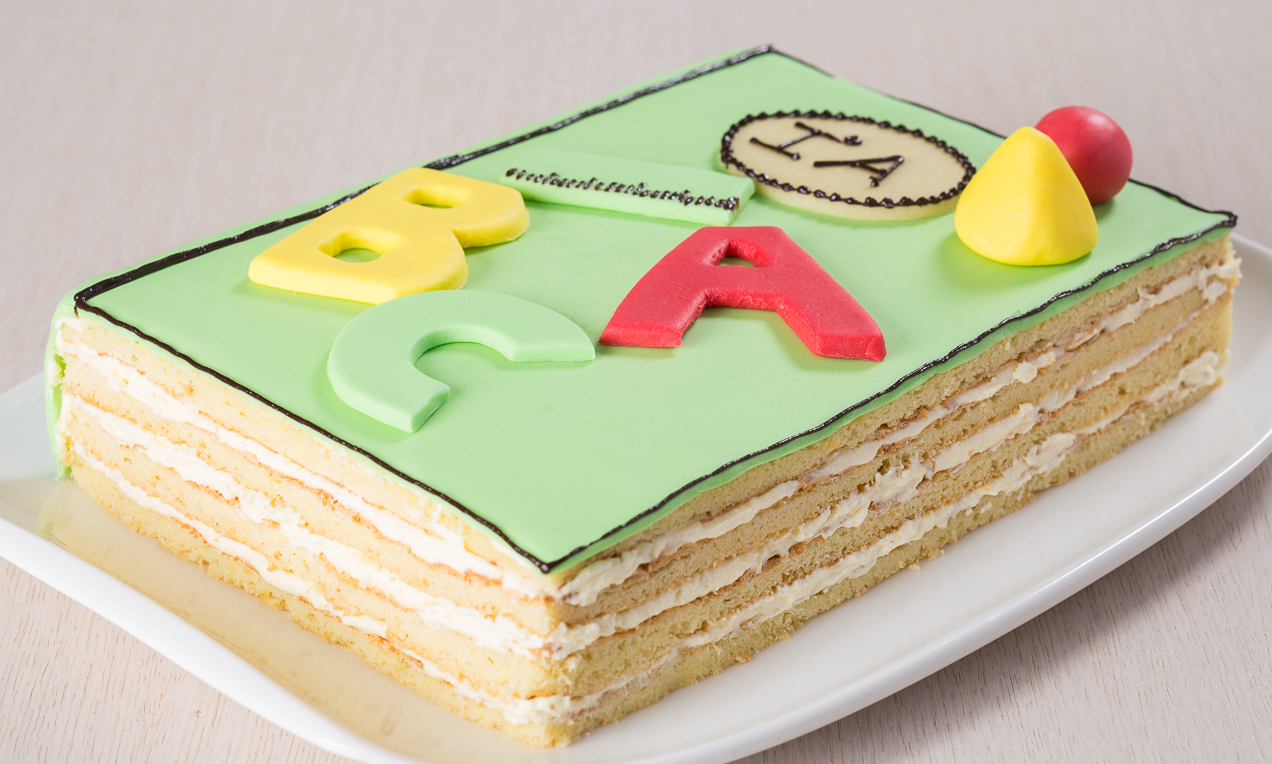 Torta alla crema chantilly a forma di libro con decorazioni di marzapane