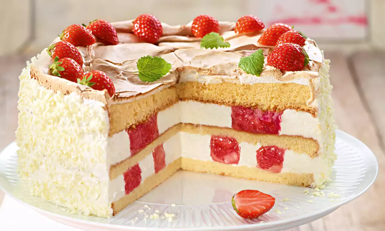 Rhabarber-Erdbeer-Baiser-Torte mit hellen Schichten aus Creme und Teig, rot-weißen Fruchtstücken, knusprigem Baiser und frischen Erdbeeren