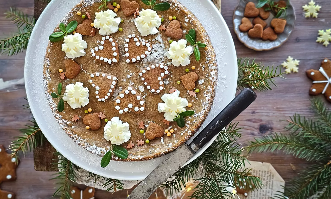 Vaalea pehmeä piparinen kladdkaka valkoisella lautasella, koristeltuna kermavaahdolla, sydänpipareilla ja värillisillä strösseleillä