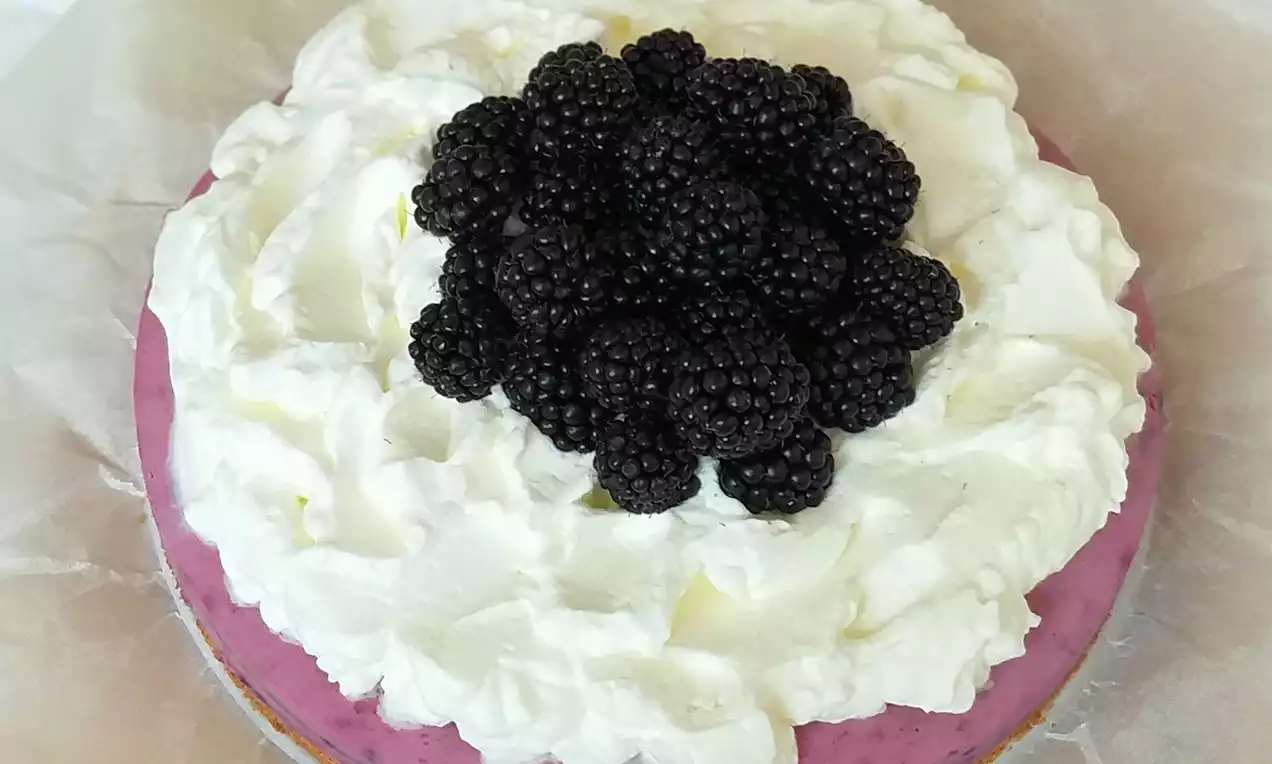 Ostružinový dort s fialovým krémem, vrstvou nadýchané bílé šlehačky a kupou lesklých tmavých ostružin na pergamenovém papíře