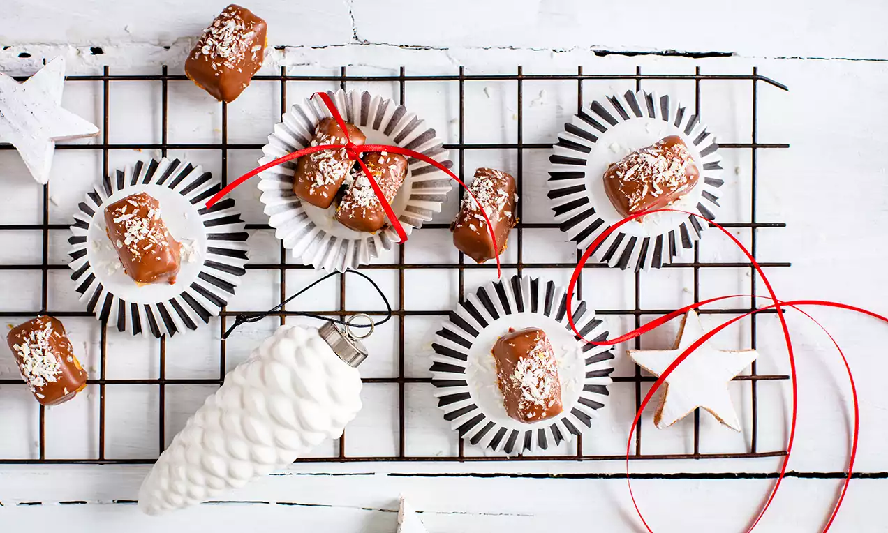 Vanilkové tyčinky poliate lesklým karamelom, posypané strúhaným kokosom, naaranžované v čierno-bielych košíčkoch na mriežke