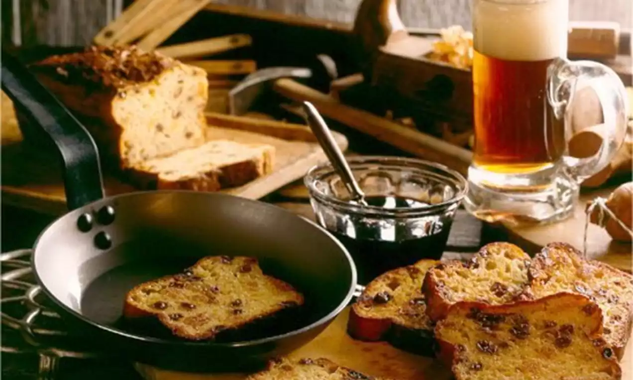 Westfälischer Kastenpickert hellbraun und mit Rosinen gesprenkelt, in Scheiben angebraten in einer schwarzen Pfanne, serviert mit Bier und Marmelade