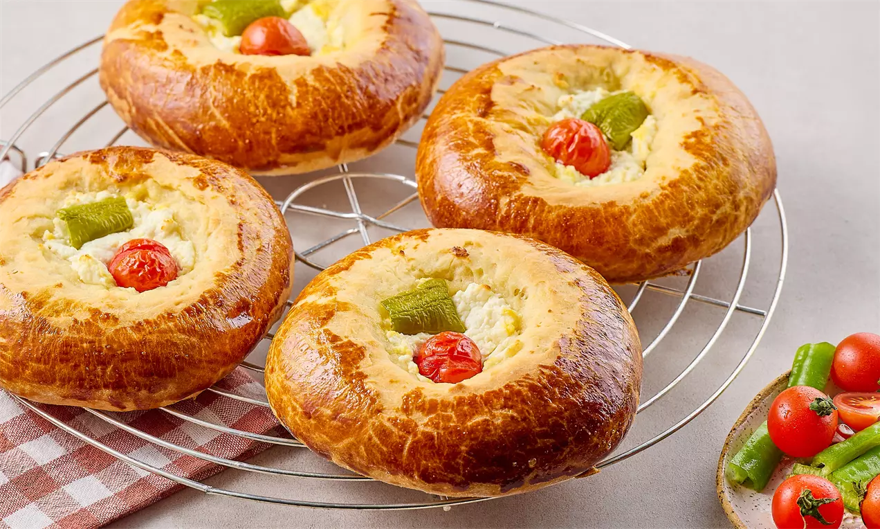 Altın rengi kabarık hamurlar, ortasında eriyen beyaz peynir, parlak cherry domates ve çıtır biber dilimleriyle tel ızgarada sunulmuş