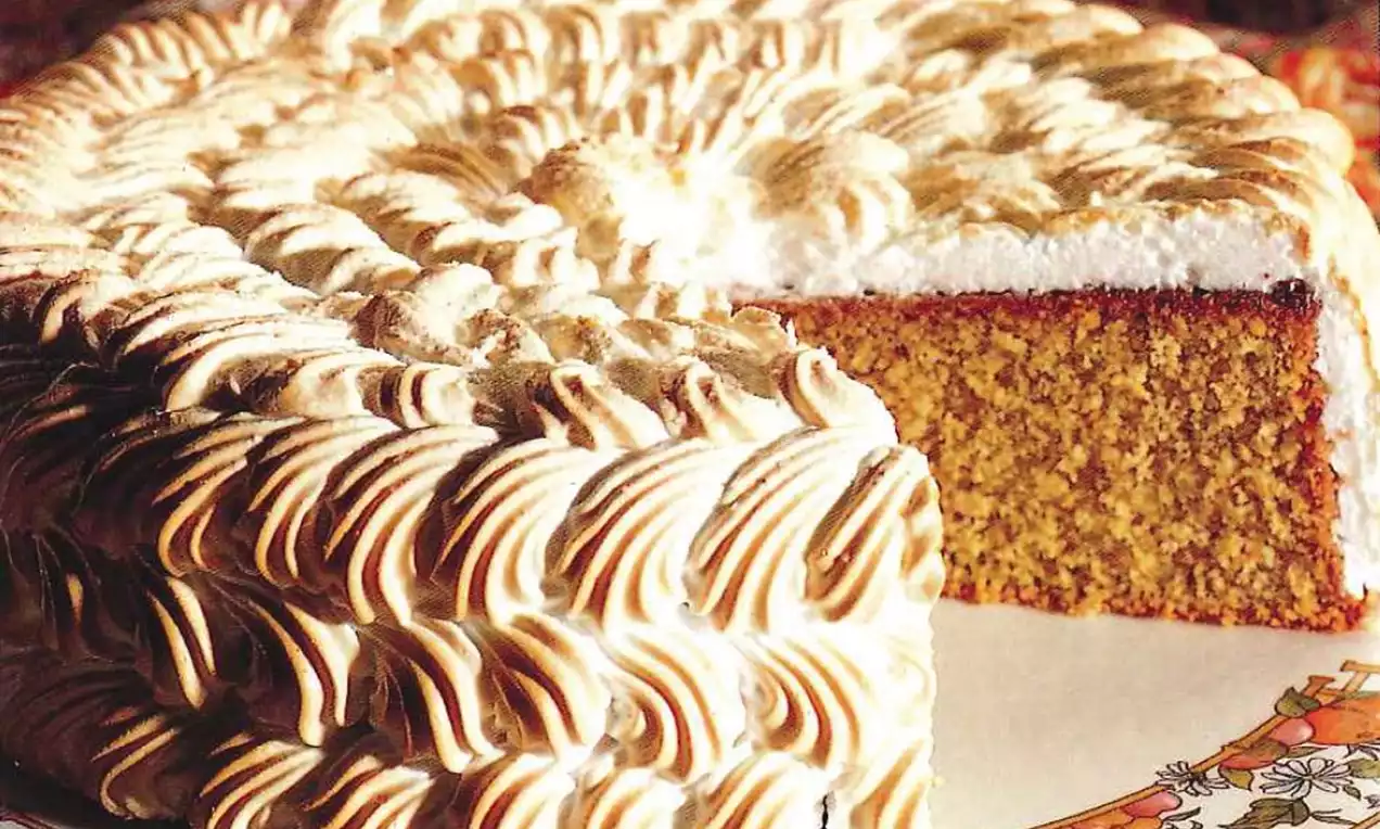 Gâteau moelleux vert doré avec une spirale de crème meringuée bicolore, posé sur une assiette décorée aux motifs floraux