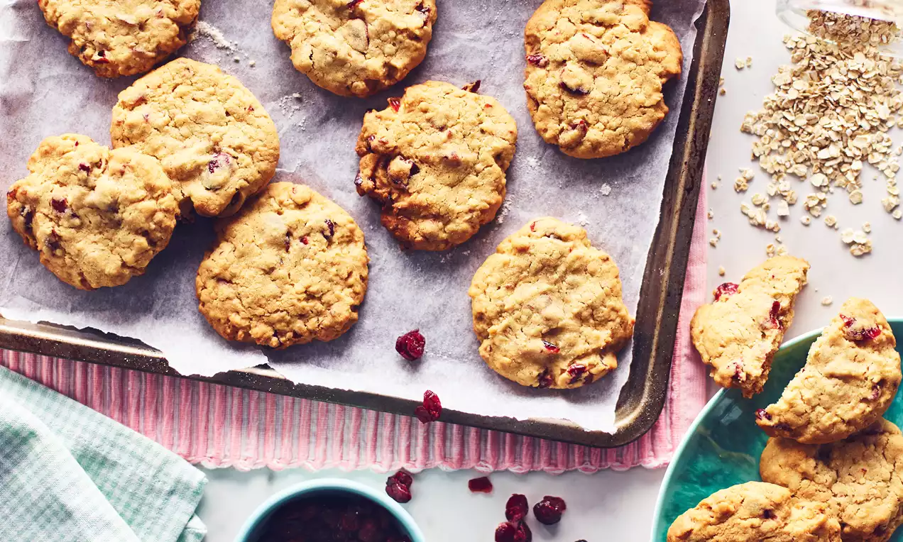 Cranberry and almond cookies golden and slightly uneven in shape with a crumbly texture on a baking tray lined with parchment paper
