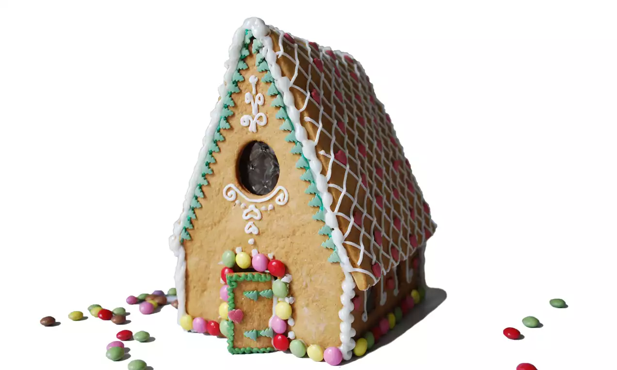 Färgglatt pepparkakshus med vit glasyr, mönstrat tak, runda fönster och spritsade detaljer, dekorerat med färgglada godisbitar